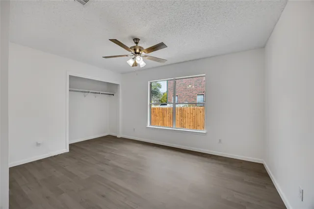 an empty room with a window and a ceiling fan