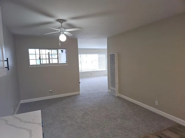 an empty room with windows and chandelier fan