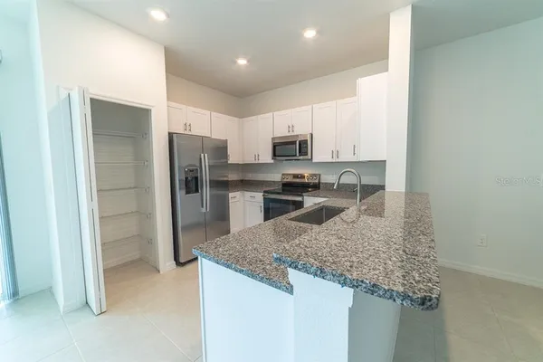 a kitchen with kitchen island granite countertop a refrigerator and a sink