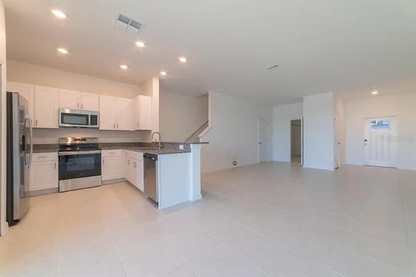 a kitchen with stainless steel appliances kitchen island granite countertop a stove top oven a sink and white cabinets