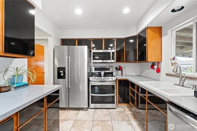 a kitchen with stainless steel appliances a stove a sink and a refrigerator