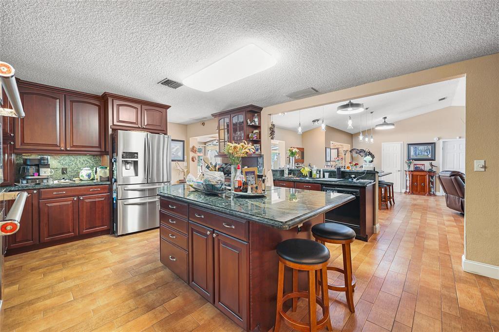 9700 Northwest 28th Street Hollywood, FL 33024 - Photo 27 of 76 a kitchen with stainless steel appliances kitchen island granite countertop a table and chairs in it