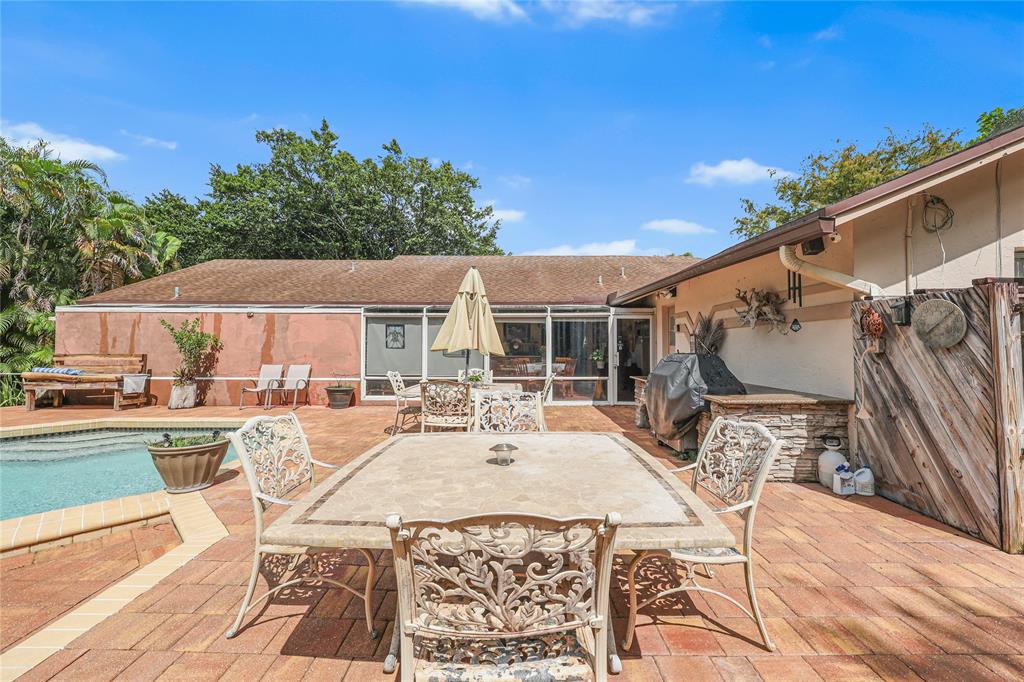 9700 Northwest 28th Street Hollywood, FL 33024 - Photo 41 of 76 a view of a patio with couches table and chairs under an umbrella with a barbeque