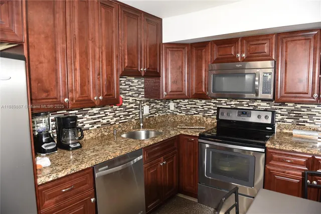 a kitchen with granite countertop a stove a microwave a sink and cabinets