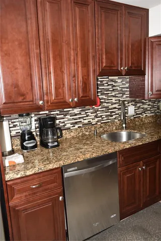 a kitchen with granite countertop stainless steel appliances a sink a stove a counter space and cabinets