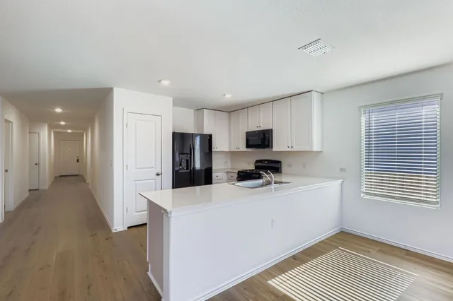 a kitchen with stainless steel appliances a sink a stove a refrigerator cabinets and a window