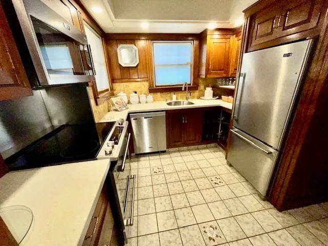 a kitchen with stainless steel appliances a sink a stove top oven a counter space and cabinets