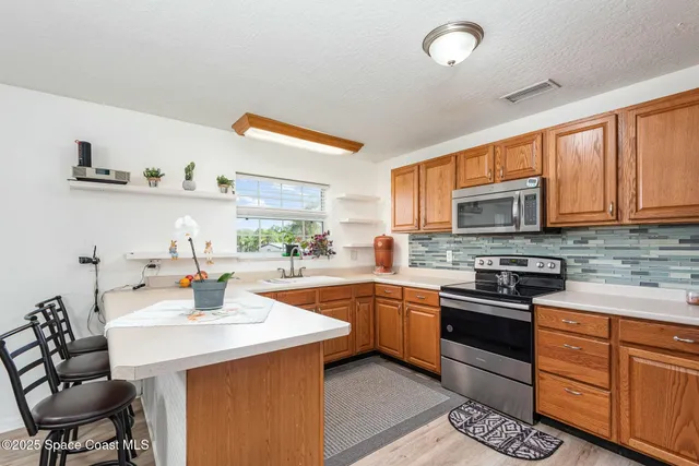 a kitchen with stainless steel appliances a sink a stove a refrigerator cabinets and dining table