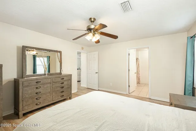 a bedroom with a bed a dresser and a chandelier