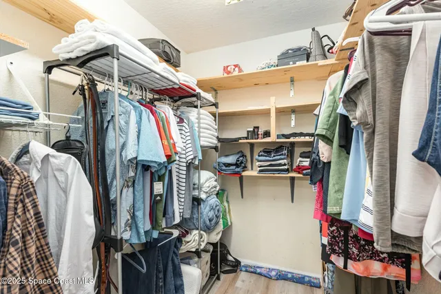 a view of walk in closet with clothes and shoes