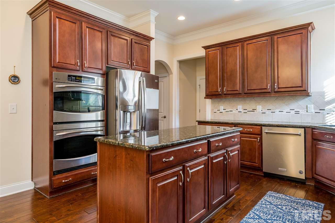 1528 Rodessa Run Raleigh, NC 27607 - Photo 13 of 30 Double ovens, stainless appliances, corner window over the sink, island, glass front cabinet, tile backsplash and recessed lighting make this kitchen a dream for cooking and entertaining.