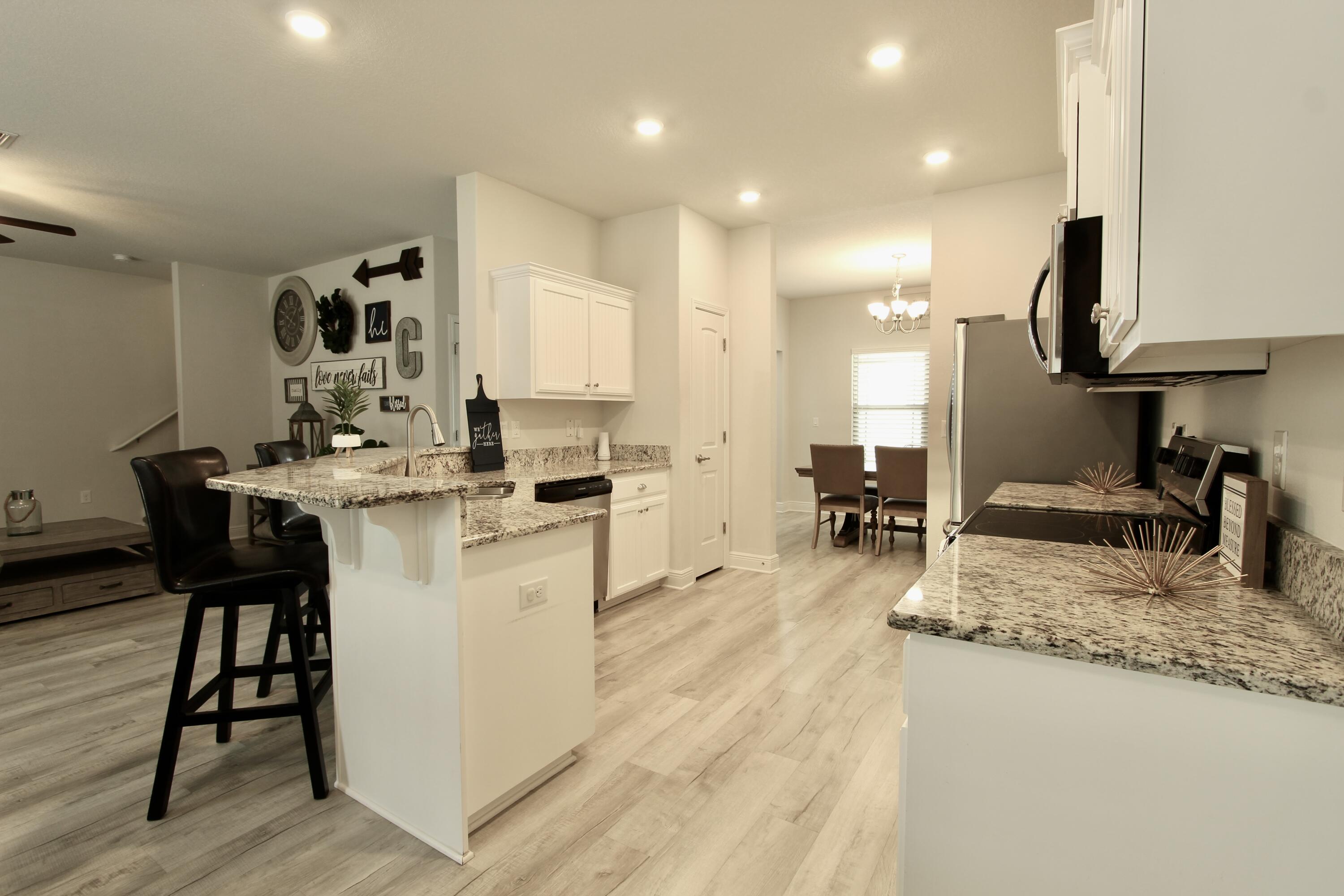 5755 Marigold Loop Crestview, FL 32539 - Photo 13 of 74 a kitchen with sink stove and white cabinets with wooden floor