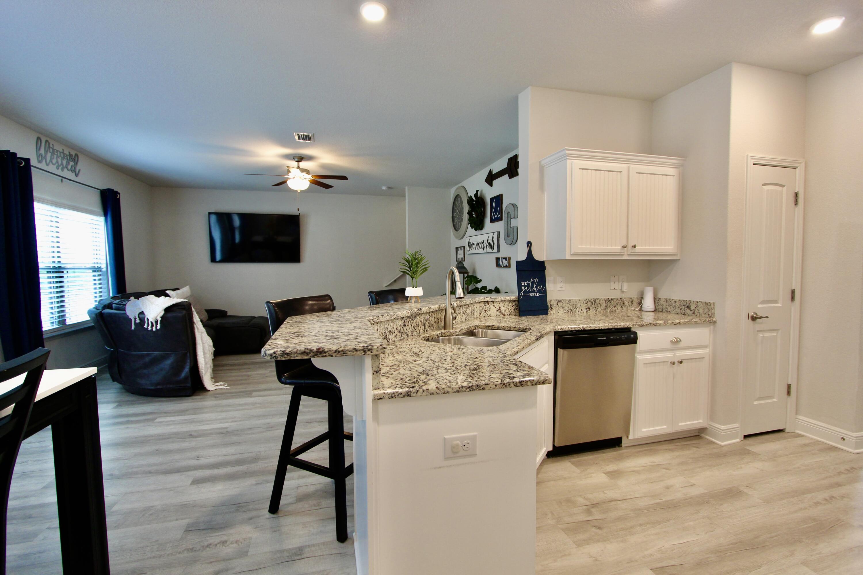 5755 Marigold Loop Crestview, FL 32539 - Photo 14 of 74 a kitchen with kitchen island granite countertop a stove top oven a sink dishwasher and a refrigerator with wooden floor