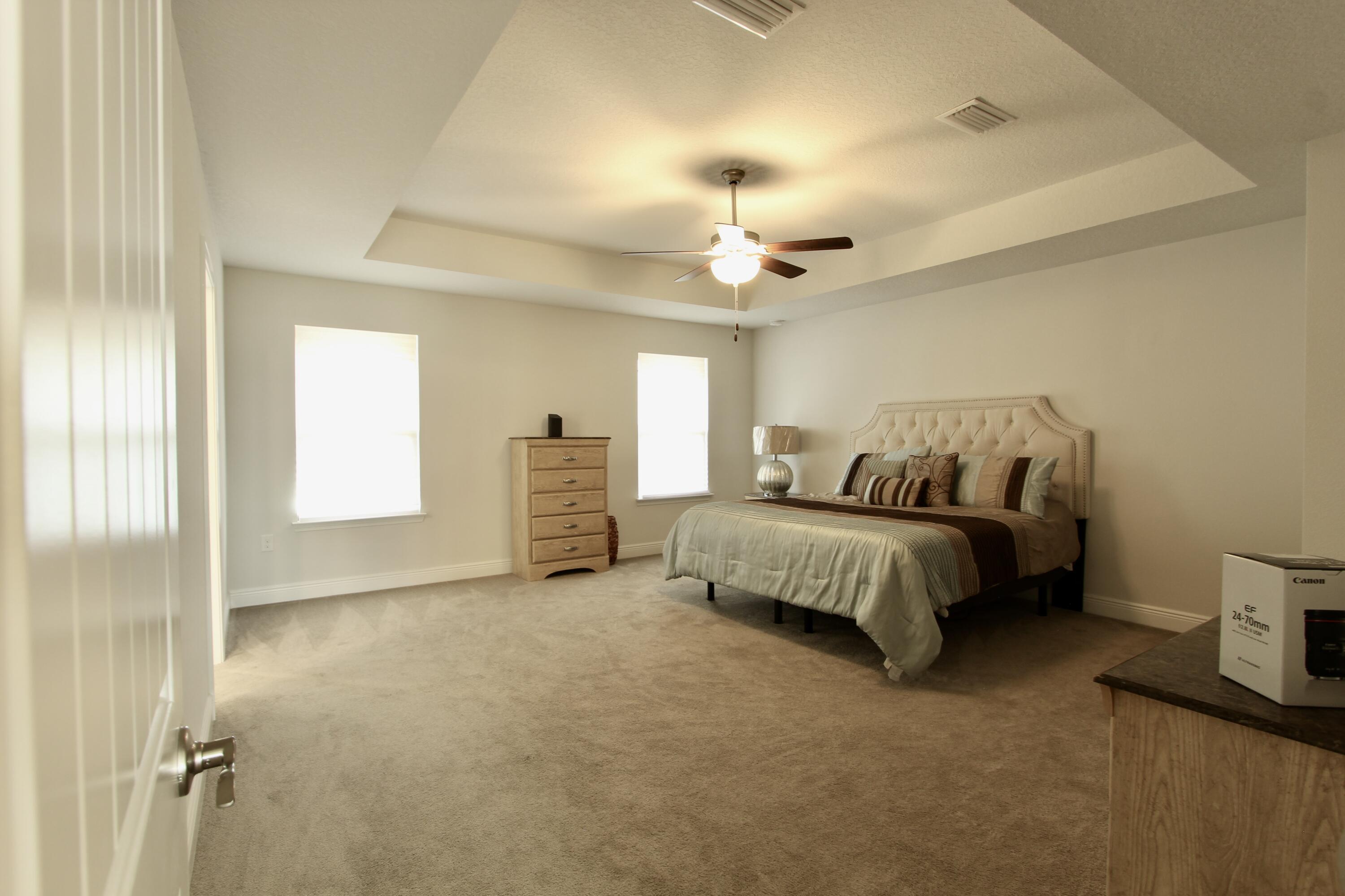 5755 Marigold Loop Crestview, FL 32539 - Photo 46 of 74 a spacious bedroom with a bed and a chandelier