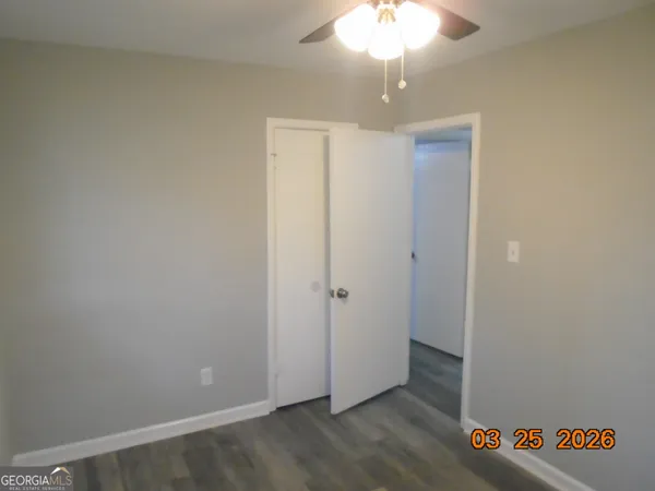 an empty room with wooden floor and chandelier fan
