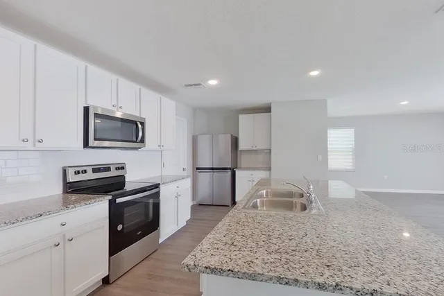 a kitchen with stainless steel appliances granite countertop a sink stove and refrigerator