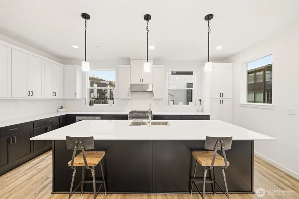a kitchen with stainless steel appliances kitchen island granite countertop a dining table chairs and white cabinets