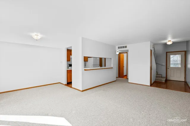a view of an empty room with kitchen and a window