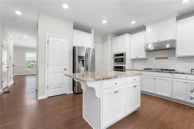 a kitchen with white cabinets and stainless steel appliances