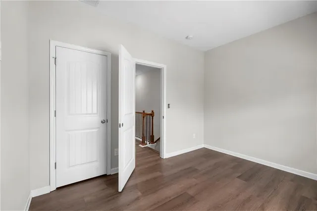 a view of an empty room with wooden floor and closet
