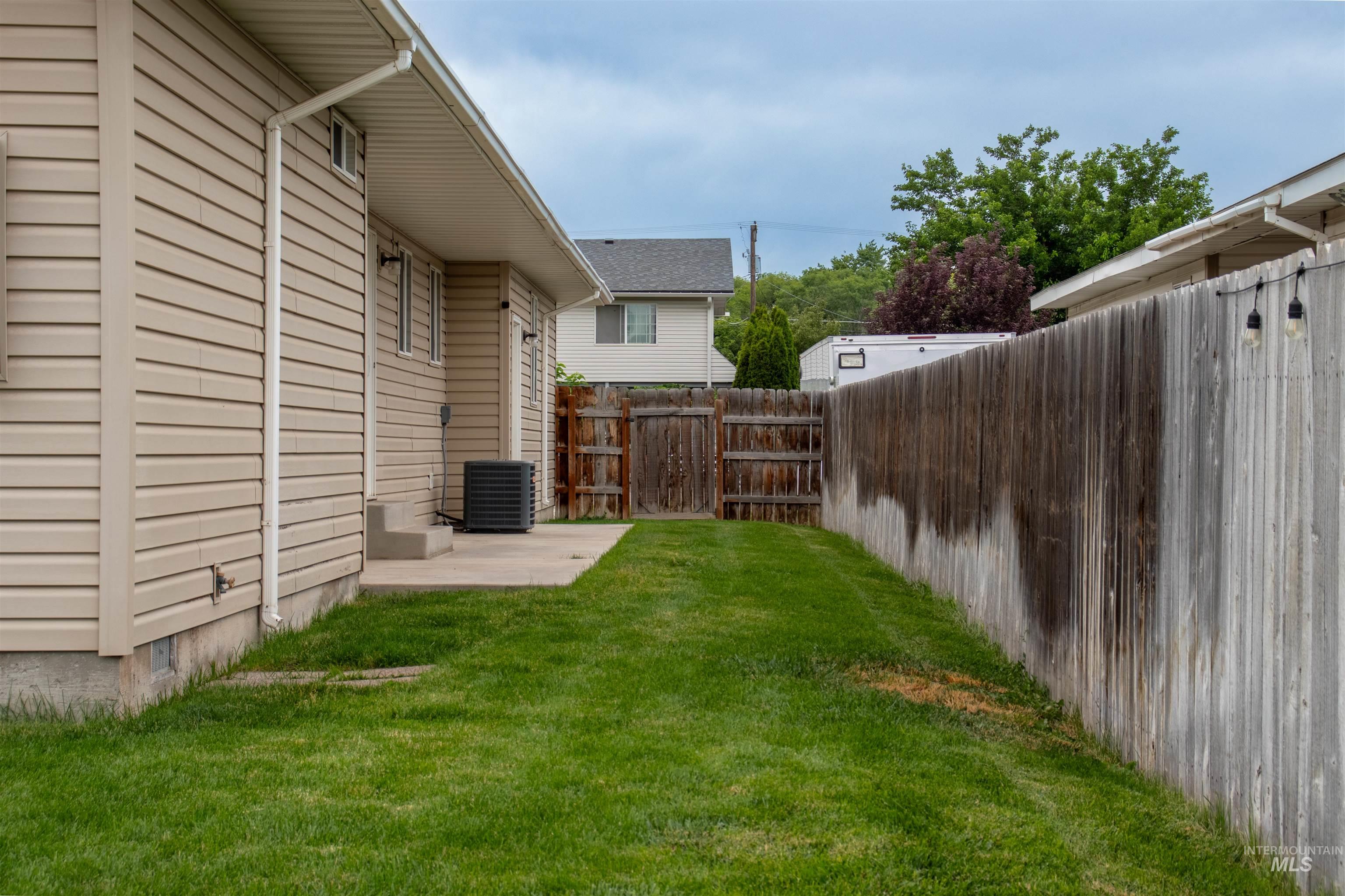 2000 M Street Heyburn, ID 83336 - Photo 14 of 15 Side yard featuring a concrete patio, wood privacy fencing, and a grass lawn