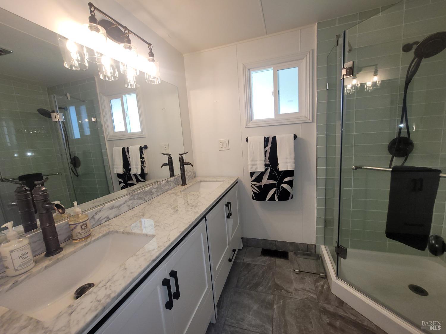 a bathroom with a double vanity sink a mirror and shower