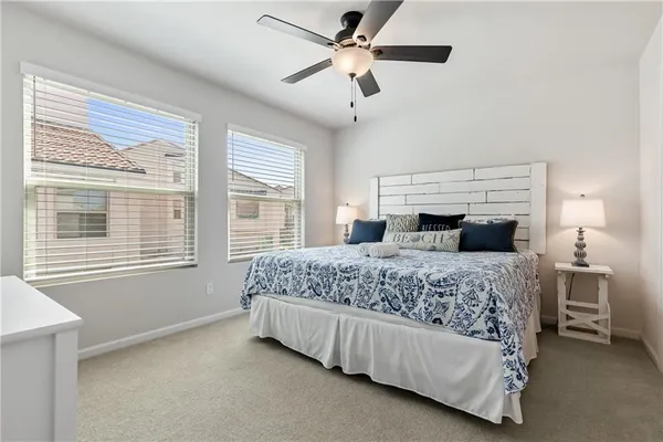 a bedroom with a large bed and a chandelier fan