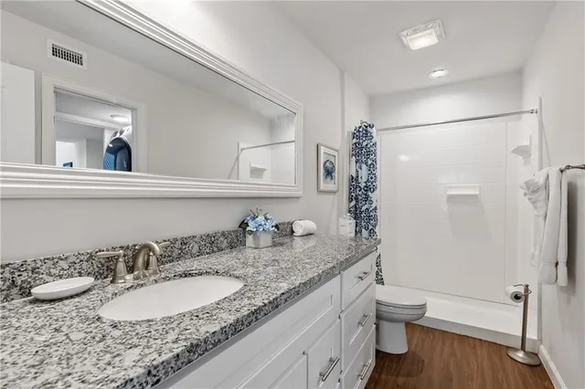a bathroom with a granite countertop sink a toilet and a mirror