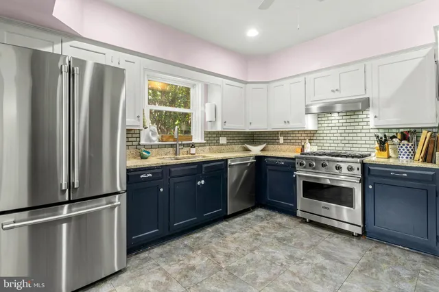 a large white bed in a bedroom next to a window and a flat screen tv