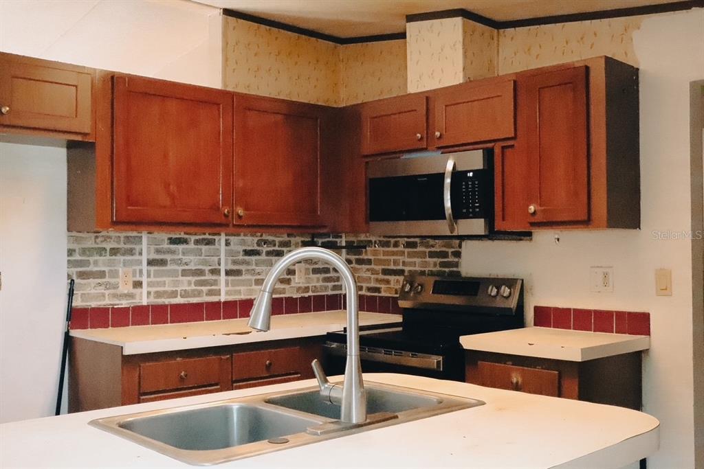 448 Fernandez Street Winter Haven, FL 33880 - Photo 14 of 27 a kitchen with stainless steel appliances wooden cabinets a stove and a microwave oven