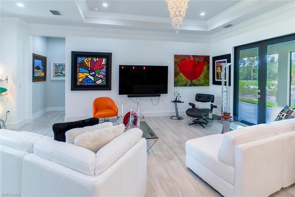 2572 Randall Boulevard Naples, FL 34120 - Photo 13 of 45 a living room with furniture a flat screen tv and a floor to ceiling window
