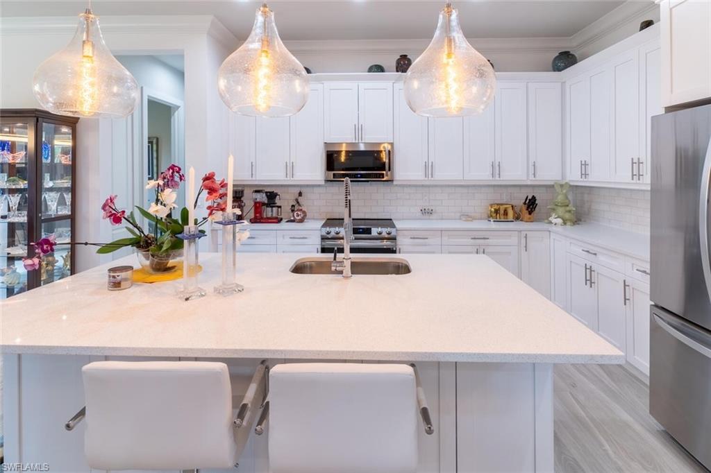 2572 Randall Boulevard Naples, FL 34120 - Photo 17 of 45 a kitchen with a sink a microwave and cabinets