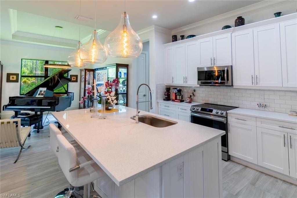 2572 Randall Boulevard Naples, FL 34120 - Photo 19 of 45 a kitchen with stainless steel appliances a stove a sink a microwave a stove and white cabinets