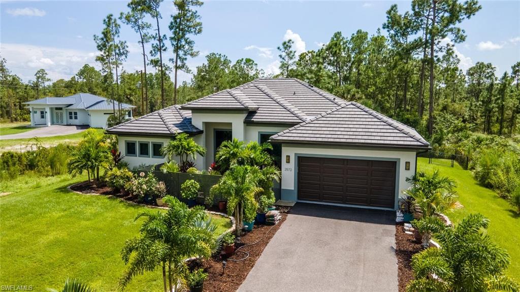 2572 Randall Boulevard Naples, FL 34120 - Photo 2 of 45 a front view of a house with a garden