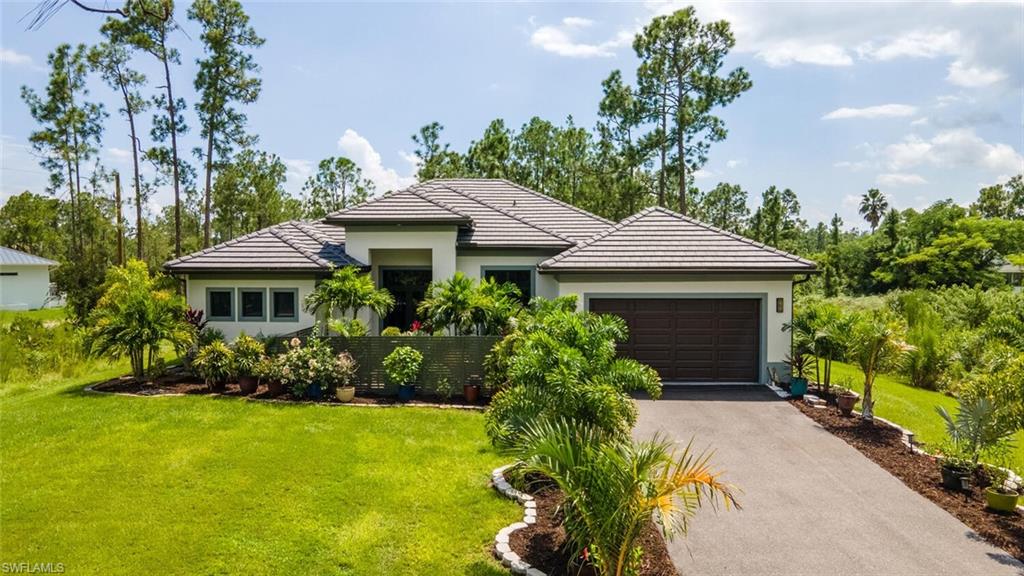 2572 Randall Boulevard Naples, FL 34120 - Photo 3 of 45 a front view of a house with a yard and potted plants