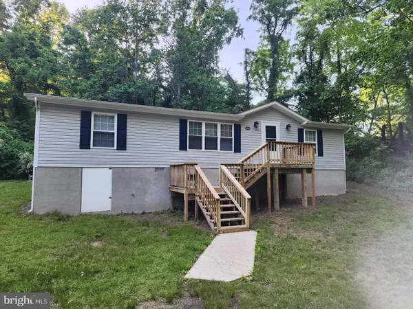 a view of a house with a yard and lawn chairs with wooden fence