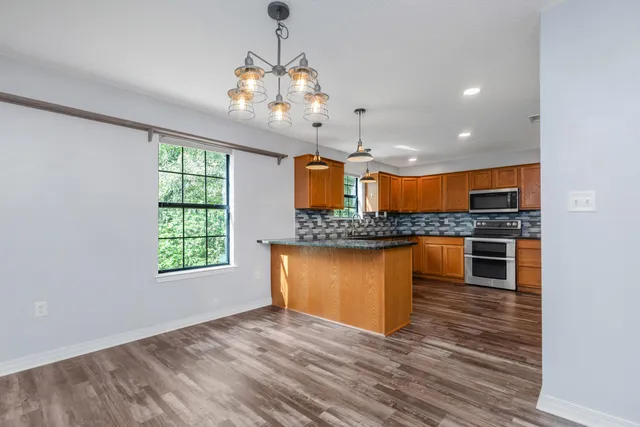 a large kitchen with stainless steel appliances granite countertop a stove and a wooden floors