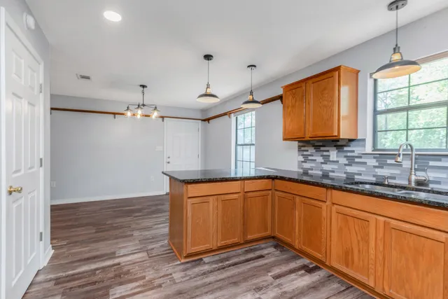 a kitchen with stainless steel appliances granite countertop a sink a stove a refrigerator cabinets and wooden floor