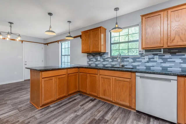 a kitchen with stainless steel appliances granite countertop wooden cabinets a sink and dishwasher with wooden floor