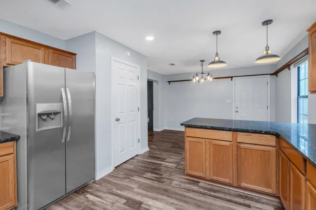 a kitchen with stainless steel appliances granite countertop a refrigerator a oven and a sink with wooden floor