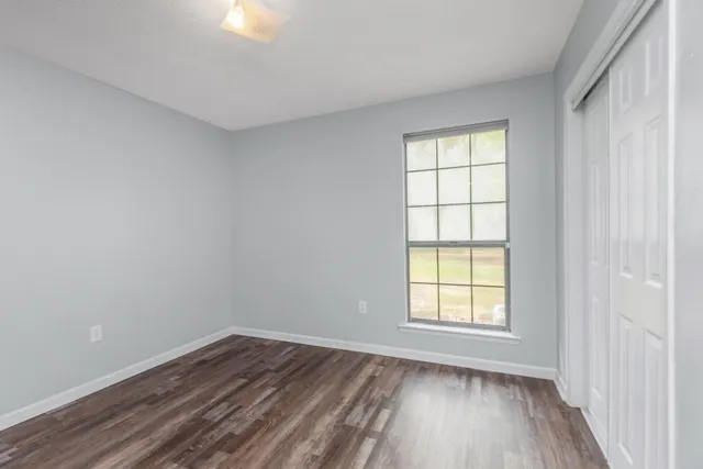 an empty room with wooden floor and windows
