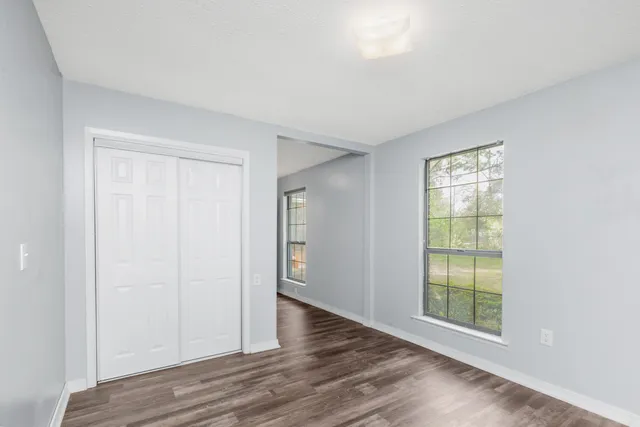 an empty room with wooden floor and windows