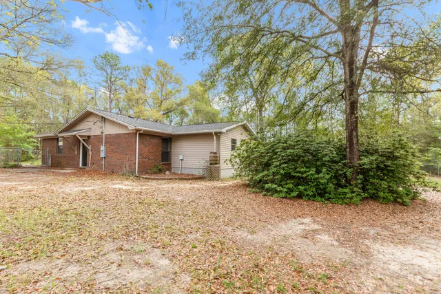 a backyard of a house with large trees and wooden fence