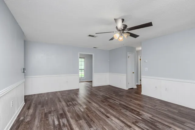 a view of empty room with wooden floor and fan
