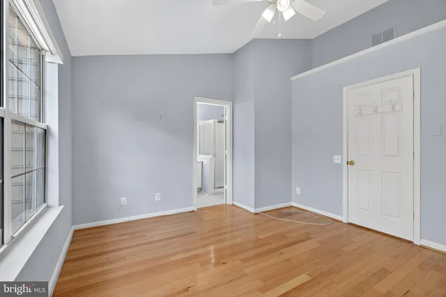 a view of empty room with wooden floor and fan