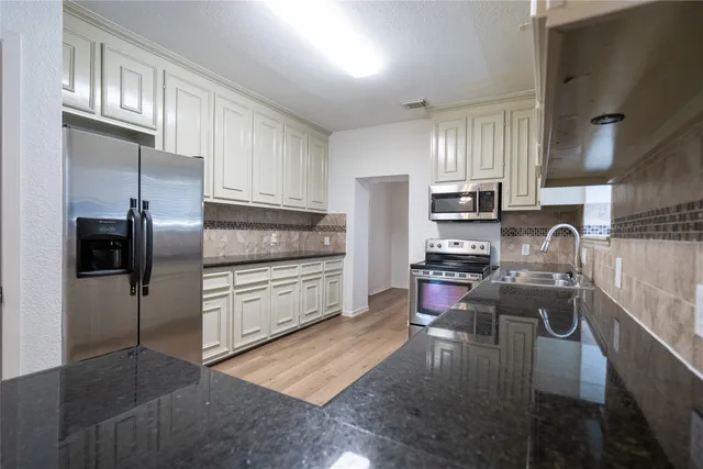 a kitchen with granite countertop a refrigerator stove and microwave