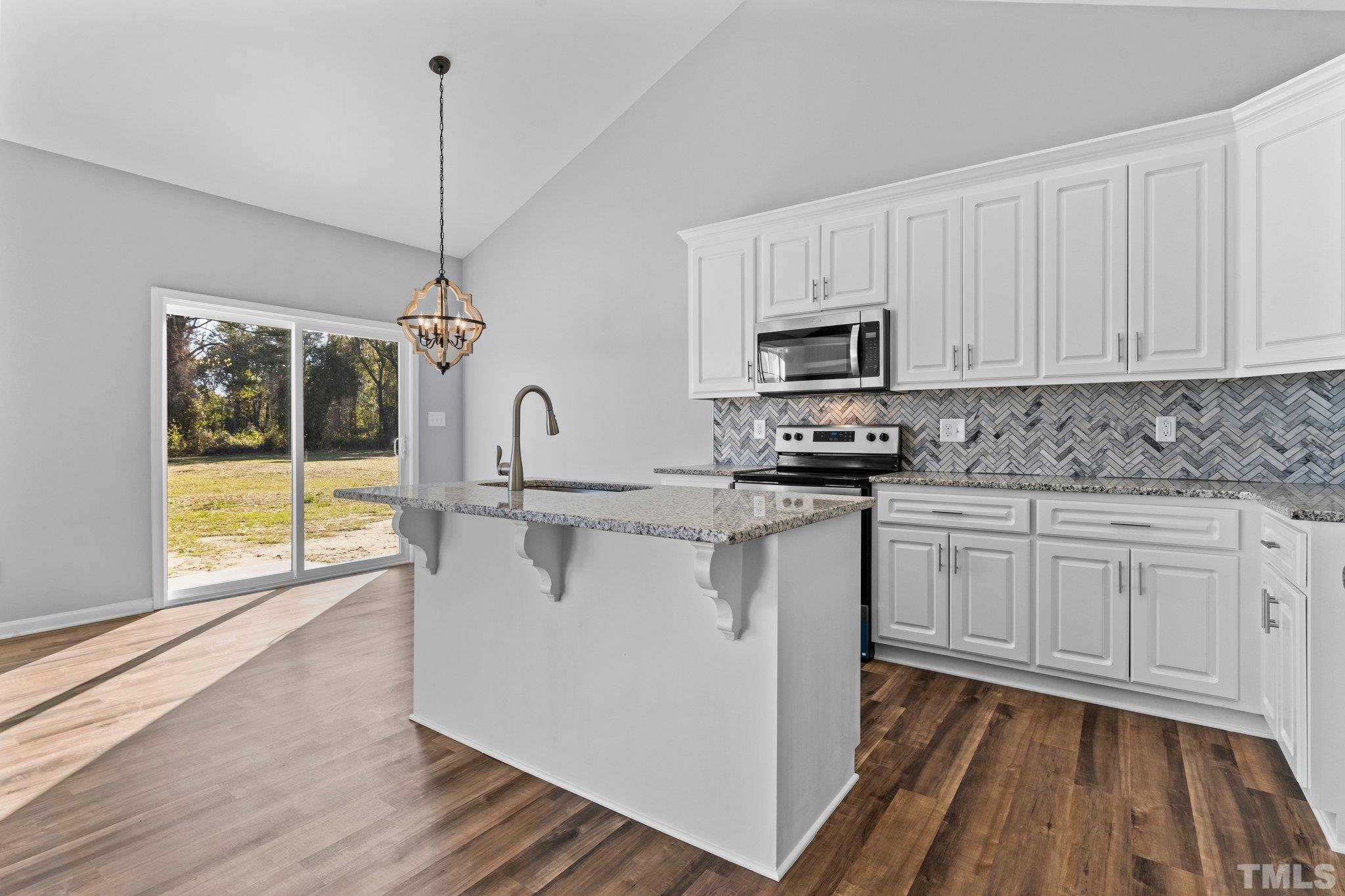9695 Chapman Road Bailey, NC 27807 - Photo 9 of 26 a kitchen with stainless steel appliances granite countertop a stove a sink and white cabinets with wooden floor