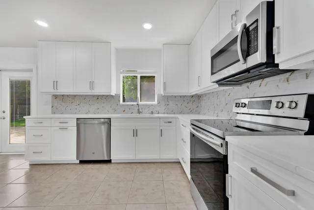 a kitchen with granite countertop white cabinets stainless steel appliances and sink