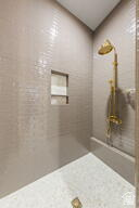 1141 East Lost Ridge Drive Washington, UT 84780 - Photo 84 of 108 Shower enclosure featuring light-toned subway tile walls, a built-in shower niche, and a gold-finish shower fixture
