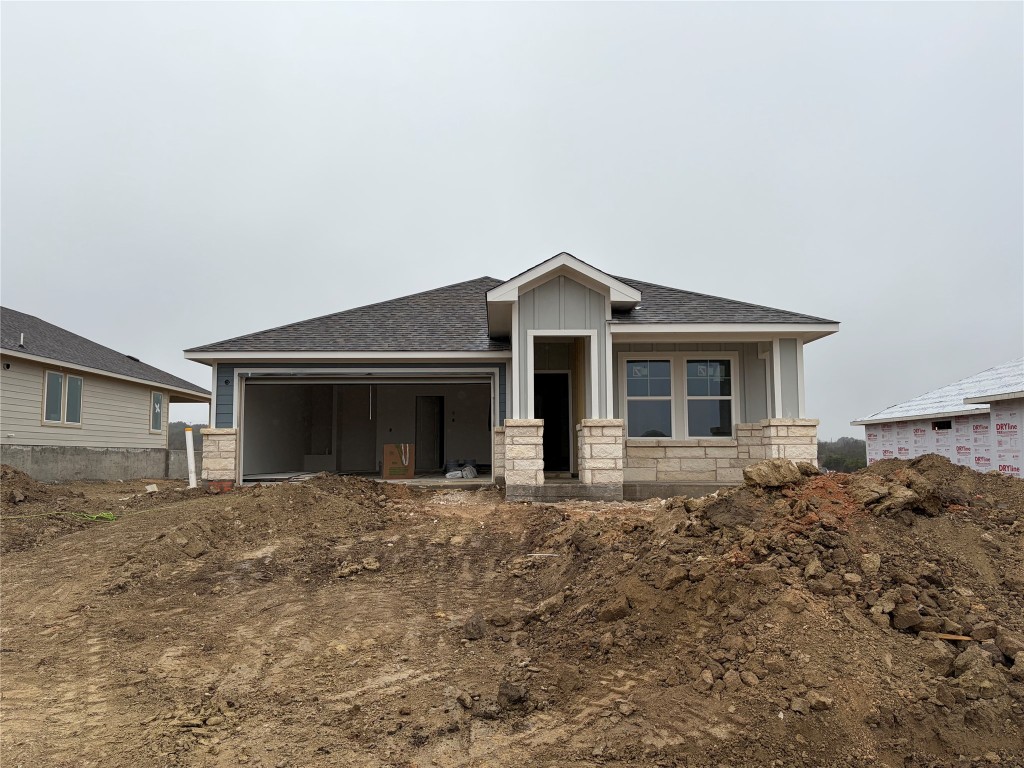 View of front of home with roof with shingles, stone siding, a porch, and board and batten siding